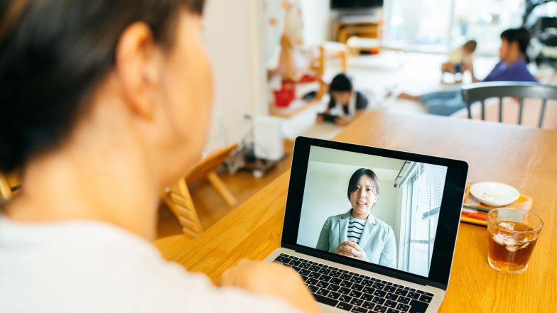 Woman on a telehealth call with children in the background